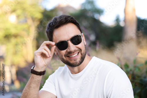 Handsome man wearing stylish sunglasses in park