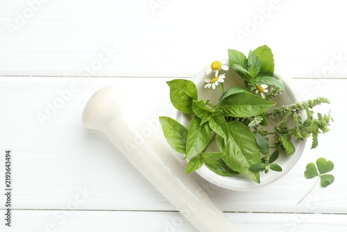 Canvastavla Mortar with pestle and herbs on white wooden table, flat lay