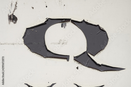 Torn Sticker on White Wall Background. Minimal closeup of white wall with torn black sticker or vinyl remnants creating abstract distressed shape. Clean grunge background, copy space, urban texture