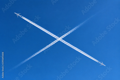 Aerial view of two jet planes crossing, creating white cross contrail.