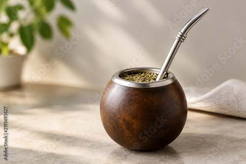 A curved silver bombilla straw contrasting with a simple mate gourd.
