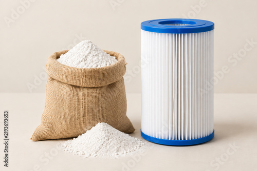 Burlap sack of white powder next to a cylindrical swimming pool filter cartridge.