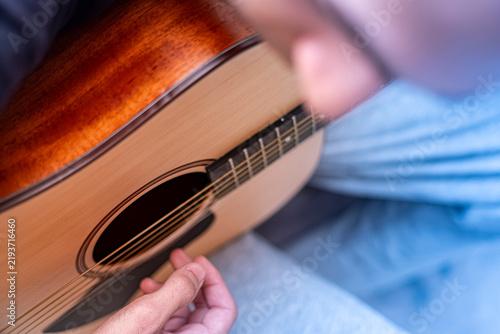 Фотография Close up of person playing acoustic wooden guitar