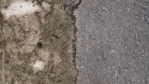 Split top-down view showing weathered mossy concrete pavement contrasting with coarse dark asphalt road surface.