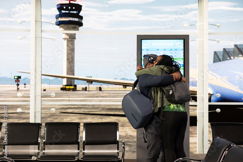 Cuadro en lienzo Black couple embrace in an airport terminal after reuniting expressing affection and relief as the young man and woman meet again at arrivals