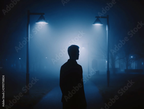 Human Silhouette Under Streetlights in Blue Fog