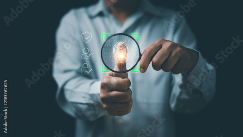 Biometric authentication concept. Hand holding magnifying glass scanning a digital fingerprint. Representing identity verification, secure access, cybersecurity, privacy and personal data protection.