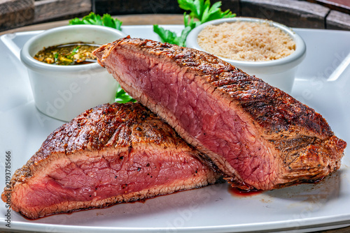 Cuadro en lienzo Bife grelhado malpassado e fatiado em um prato branco, com farofa tradicional e molho chimichurri