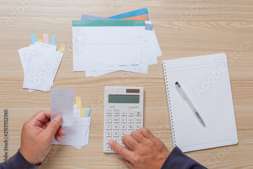 Calculating receipt expenses with calculator while preparing a tax return at home