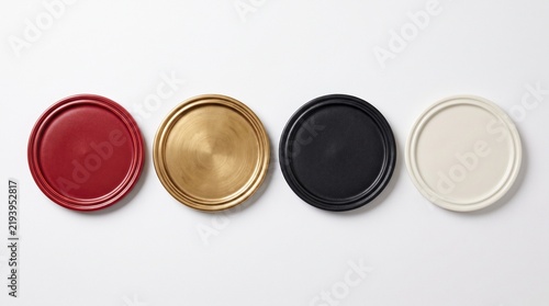 Four round coasters in red gold black and white on plain surface