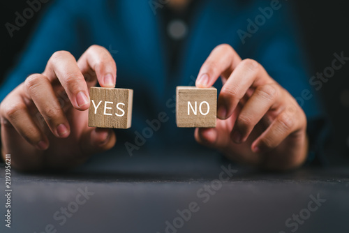 Think With Yes Or No Choice, Business Choices For Difficult Situations, Yes or no and question mark, man holding two wooden with yes or no word on it, making decision.