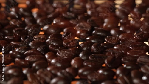Roasted coffee beans moving over an open flame during the coffee roasting and grinding process, highlighting the dynamic movement and texture of the beans in a close-up cinematic shot.