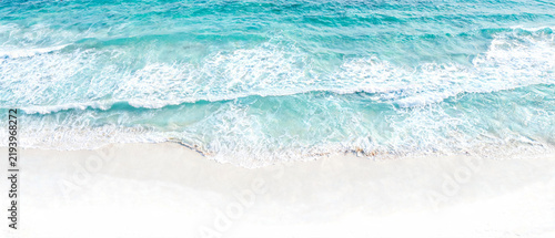 Aerial view of turquoise ocean waves breaking on white beach