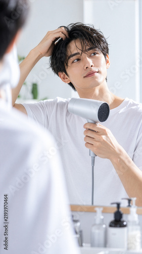 ドライヤーでヘアセットする若い男性