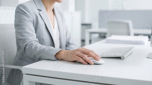 Professional Woman in Grey Suit Working with Computer Mouse on White Office Desk