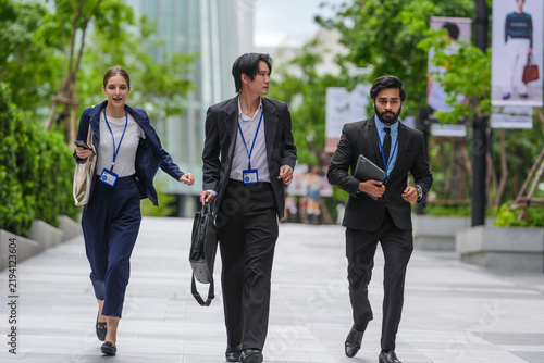 Foto Three young business professionals wearing conference badges walk three abreast