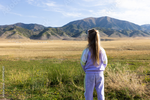 Картината върху платно Woman In Sweater Standing On Meadow Path With Mountain Landscape in Xinjiang pro