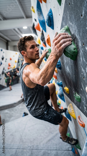 Man climbing an indoor bouldering wall in a modern gym