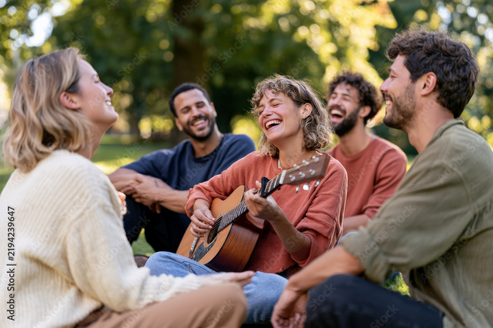 Obraz premium Diverse friends sing and play guitar together outdoors. Live music, joyful gathering, social connection.