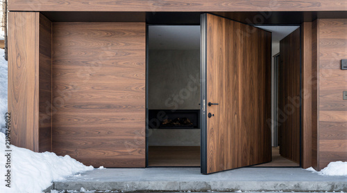 Modern exterior featuring 3000mm by 1500mm solid walnut door pivoting on 50mm diameter concealed floor mount