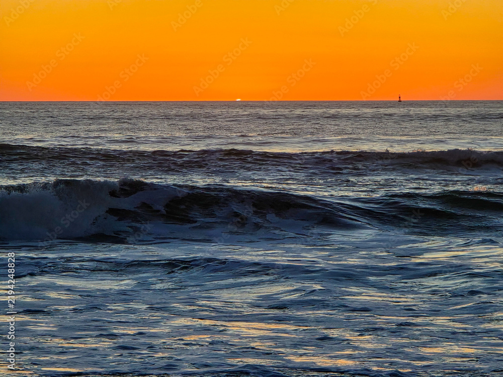 Obraz premium Ocean Waves at Sunset With Sun Disappearing Below Horizon