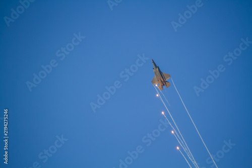 F-35A Lightning II fighter aircraft flying across a blue sky with visible vapor trails and clouds below, photographed in side profile showing its distinctive stealth aircraft design.