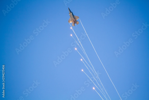 F-35A Lightning II fighter aircraft flying across a blue sky with visible vapor trails and clouds below, photographed in side profile showing its distinctive stealth aircraft design.