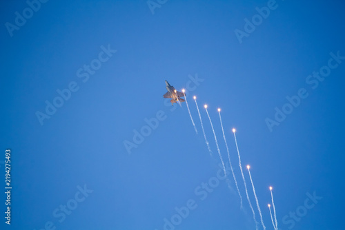 F-35A Lightning II fighter aircraft flying across a blue sky with visible vapor trails and clouds below, photographed in side profile showing its distinctive stealth aircraft design.