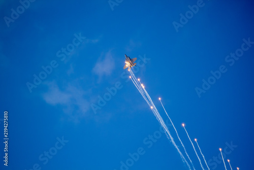 F-35A Lightning II fighter aircraft flying across a blue sky with visible vapor trails and clouds below, photographed in side profile showing its distinctive stealth aircraft design.