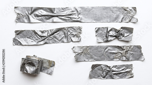 Pieces of crumpled silver grey duct tape strips on white background.