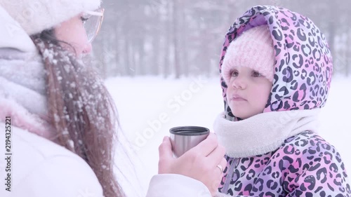 Child winter tea. Toddler drinking warm beverage outdoors. Parental care concept.