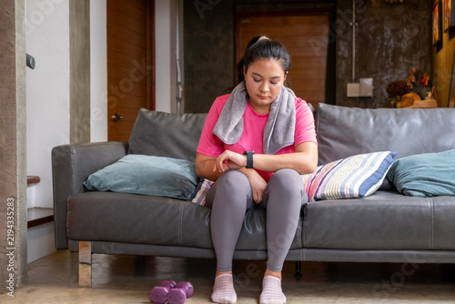 Young woman resting on sofa after fat exercise with tired expression in cozy living room
