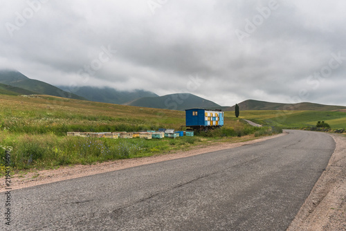 Beehives and an apiary on a rural mountain road amidst blooming meadows in Kyrgyzstan.