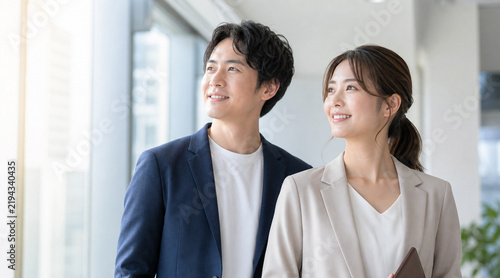 Plakat 明るい窓辺で希望に満ちた表情で未来を見つめる会社員の若い男女