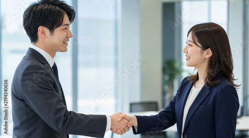 Plakat 明るいオフィスで笑顔で固い握手を交わすビジネスパーソンの男女