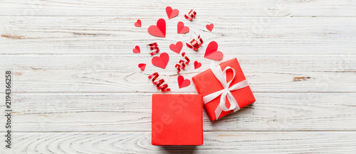 Happy valentines day opened heart shape gift box with small hearts, on colored background, valentines day card - top view concept