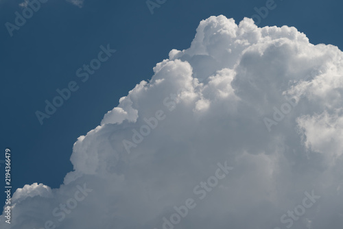 Towering white cumulus cloud against a deep blue sky