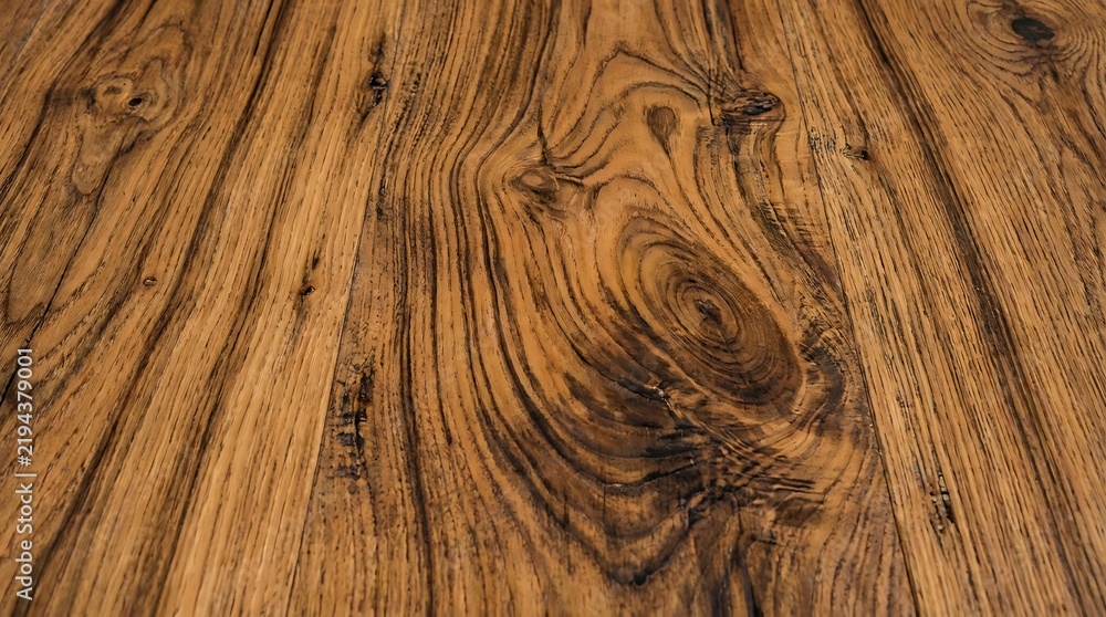 Obraz premium Natural dark brown wooden surface showing intricate grain patterns and rustic knots captured from a high angle perspective to emphasize the rich organic timber texture