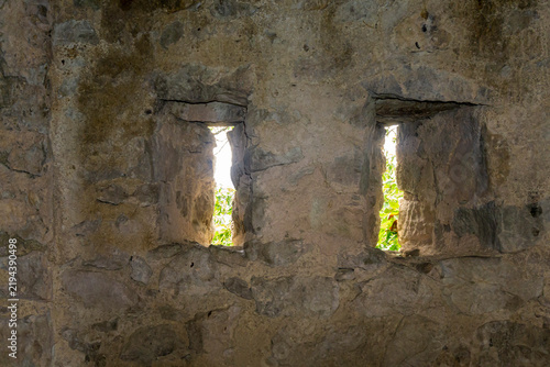 Two gun slits in a wall of light-colored stones of varying shapes and sizes, cemented together with lime. Medieval masonry. Amlivi, Amlevi complex. Kvemo Kartli, Tetritskaro, Georgia