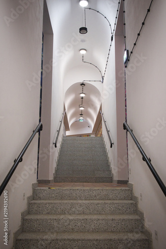 Staircase ascends under arched ceiling with recessed lights