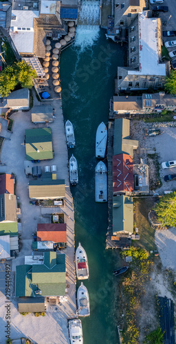 Aerial view of Historic Fishtown featuring a narrow channel with docked fishing boats and rustic wooden shanties along the waterfront in Leland, Michigan, United States.
