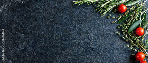 culinary herbs and ripe cherry tomatoes top view flat lay on black slate stone background frame with copy space for italian cooking recipe food menu design horizontal banner banner photography