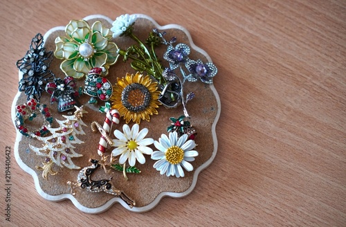 Turkey, August 20, 2025:A vintage collection of sparkling Christmas and floral brooches is displayed on a round cork board. It features enamel pins like a Christmas tree, reindeer, sunflower, daisies