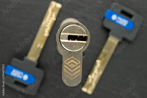 Mortise lock cylinder mechanism with keys on a piece of slate, macro shot.