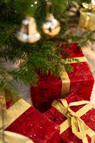 Festive Red Gifts Wrapped in Shimmering Gold Ribbons Lie Beneath the Christmas Tree