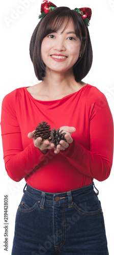Happy asian woman holding pinecone decoration promote holiday sale event wearing red shirt headband standing isolated background for christmas season celebration
