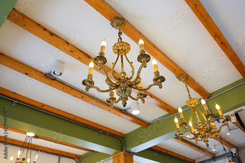 Fotografie Ornate chandelier hanging from wood beam ceiling in elegant interior with warm l