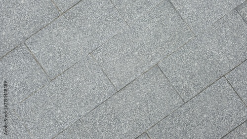 Grey granite stone flooring with diagonal brick pattern. Diagonal grey granite blocks pavement backdrop texture. Top view of rectangular grey granite tiles laid diagonally on outdoor pavement.