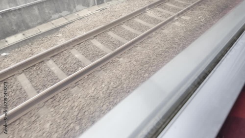 View of train tracks and railway infrastructure from a moving train window.