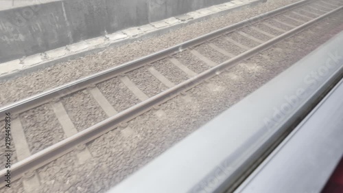 POV video shot from inside of a moving train looking out of the window at the tracks.